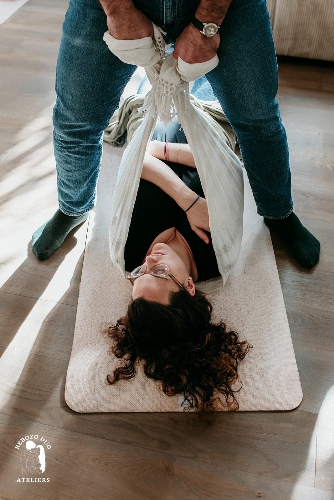 Une femme allongée sur un tapis, bercée dans un rebozo clair